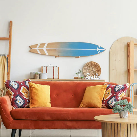 4 Piece Ash Wood Surfboard Wall Mount Kit With Curved Wave Grip mounted above an orange couch in a stylish living room.