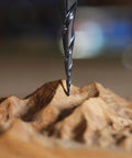 Close-up of a black tapered ball-nose carbide end mill cutting into wood.