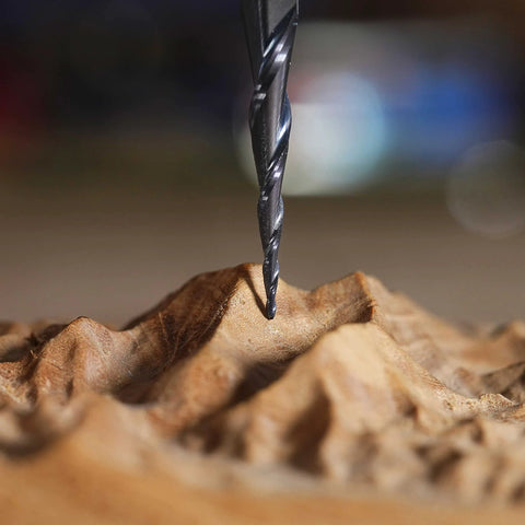Close-up of a black tapered ball-nose carbide end mill cutting into wood.