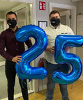 Two men holding deep navy blue number 2 and 5 balloons, 40 inch giant digit balloons for birthday backdrop, two digit party decor.