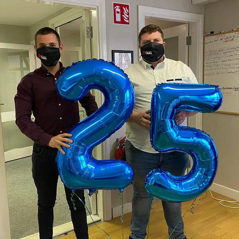 Two men holding deep navy blue number 2 and 5 balloons, 40 inch giant digit balloons for birthday backdrop, two digit party decor.
