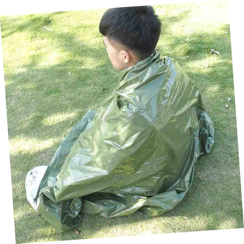 Person wrapped in olive green 3 Pack Thermal Survival Blankets Emergency Kit For Beach Mat Camping Rug Tent Ground Cover Reflective Foil Gear All In One With Emergency Signaling And Disaster Prep on grass