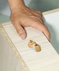 Smooth Operator Brass Concealed Barrel Hinges Six Piece Kit on a wooden cabinet with a hand, showcasing 180 degree folding design.