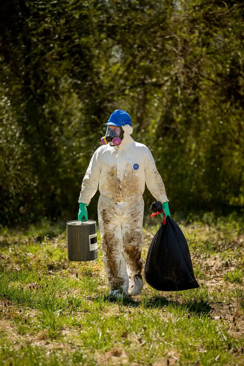 Person wearing disposable protective coverall with respirator fit hood and elastic cuffs during sanitation task outdoors