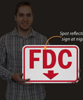 Rugged 12X18 Inch Fdc Fire Department Connection Metal Sign With Down Arrow In Red And White Using Beefy 120 Mil Aluminum Composite And 3M Reflective Film For No Fuss Install Made Stateside held by a person.