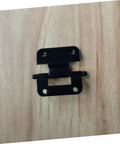 Black metal cabinet door hinge with dual mounting plates on wood surface