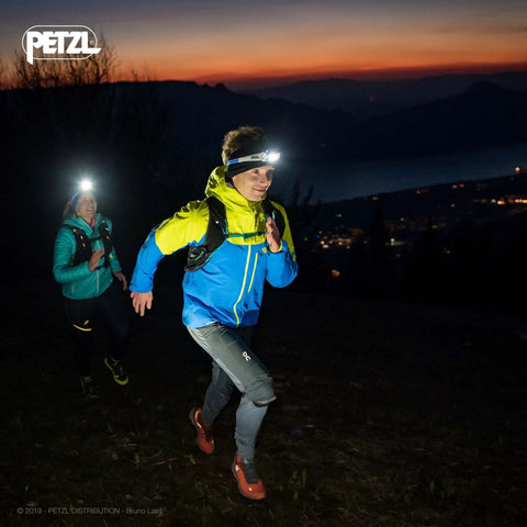 Two people trail running at dusk wearing Swift RL Rechargeable Headlamp With Reactive Lighting Technology, 900 Lumens, Blue.