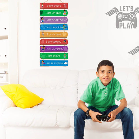 Boy sitting on couch with Set Of 9 Rainbow Themed Wood Wall Plaques For Boys Room With Inspirational Quotes Hanging Signs visible