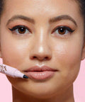 Close-up of a model holding a Reusable Waterproof Makeup Remover Pen for quick lipstick fixes with a fine tip.