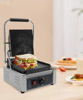 1800W Commercial Panini Grill Press With Stainless Steel Body And Cast Iron Plates grilling sandwich with vegetables on countertop.