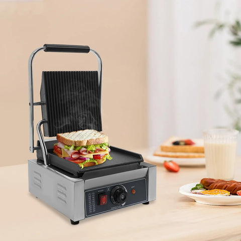 1800W Commercial Panini Grill Press With Stainless Steel Body And Cast Iron Plates grilling sandwich with vegetables on countertop.