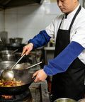 Tough As Nails Heat Resistant Welding Sleeves Fireproof Arm Protectors Zero Sweat Breathable Wrap Pro Grade Armor For Scorching Shop Grind And Heavy Auto Repair Blue worn by chef stirring food in wok.