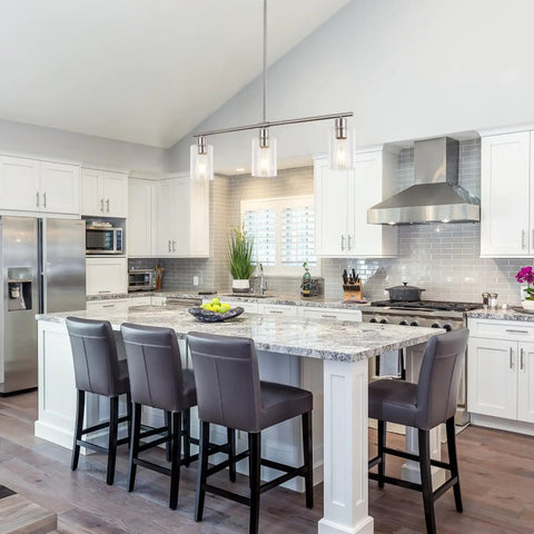 Three Light Modern Chandeliers For Kitchen Island Lighting In Brushed Nickel With Clear Glass Pendants Adjustable Height Linear Ceiling Mount Perfect For Dining Room Farmhouse Vibe over a kitchen island with gray chairs.