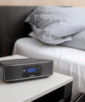 Exos Home Speaker With 30W RMS Power, Bluetooth Streaming, CD Player, on bedside table with modern digital display