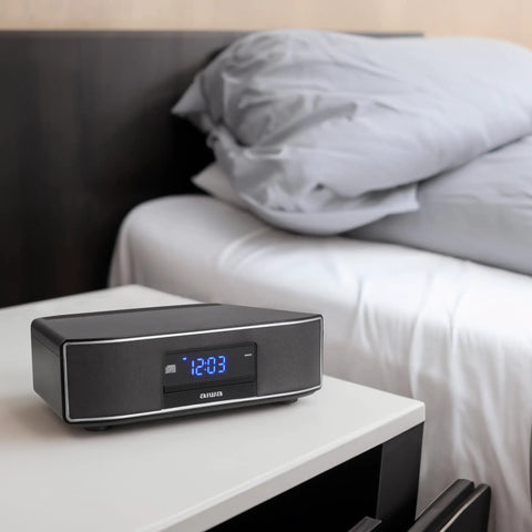 Exos Home Speaker With 30W RMS Power, Bluetooth Streaming, CD Player, on bedside table with modern digital display