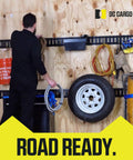 Person organizing tools and tire on wall with E-Track system, using Heavy Duty Retractable Ratchet Straps For E Track And Bolt On Mounting Pack Of 2 1 Inch By 6 Feet 4000 Lbs Break Strength Auto Self Retracting Tie Downs visible.