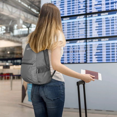 Traveler with Lightweight 20L Packable Backpack for Travel And Hiking Foldable Daypack at airport holding passport and suitcase