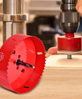 4-inch red HSS bi-metal hole saw with pilot bit, shown with a drill on a wood surface