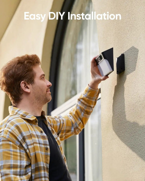 Person installing All In One Solar Wall Light Camera With 8GB Storage For Outdoor Security on wall, easy DIY installation.