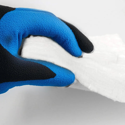 Ceramic fiber blanket insulation, white, held by blue-black gloved hand.
