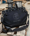 Deluxe 16 Inch Canvas Tool Bag With 13 Pockets And Detachable Shoulder Strap, Black, showing leather handles in workshop.