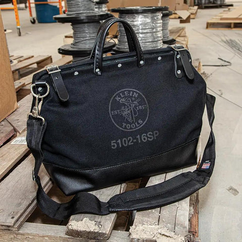 Deluxe 16 Inch Canvas Tool Bag With 13 Pockets And Detachable Shoulder Strap, Black, showing leather handles in workshop.