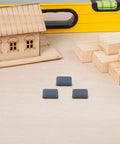 Three PTFE furniture sliders from 12 Pack PTFE Furniture Sliders for Carpet on wooden surface near construction tools.