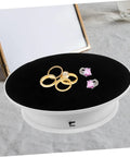 Premium Rotating Jewelry Display Stand With Smooth Electric Turntable Spin, showcasing rings and earrings on a black velvet surface.