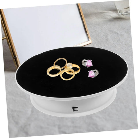 Premium Rotating Jewelry Display Stand With Smooth Electric Turntable Spin, showcasing rings and earrings on a black velvet surface.