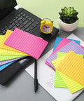 Huge 4x6 Lined Sticky Notes 12 Pack With 30 Sheets Per Pad, Ultra Sticky Notes in bright colors displayed on a desk next to a laptop.