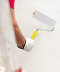 Hand using a mini white sponge paint roller cover on a textured wall, showcasing the Ten Pack Of White Sponge Paint Roller Covers For Walls And Ceilings No Drama Mini Size Slick Operation Great For Diy Renos Quick Change Design Smooth Operator Finish Every Time.
