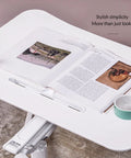 Mobile Standing Desk With Pneumatic Height Adjustment Rolling Sit Stand Cart Riser Low Profile Couch Bed Desk Smooth Roll Home Office Studio Podium Wide Work Surface with open book and coffee cup.