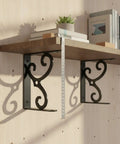 Ornate black metal shelf brackets supporting a wooden shelf with books and a plant