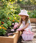 Child using Eight Piece Kids Gardening Tool Set With Shovel Rake Watering Can Hat Apron Gloves And Storage Bag Pink Flower Theme