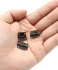 Hand holding three Bronze Mini Jewelry Box Hinges Set Of 60 With Screws For Diy Projects And Crafts On Wooden Boxes And Cases Antique 