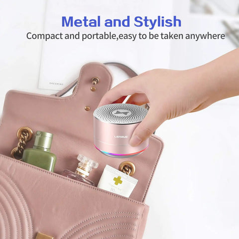 Hand placing Tiny But Mighty Grab And Go Metal Bluetooth Speaker With Lights And Lanyard 5W Mini Wireless 5.0 into a handbag.