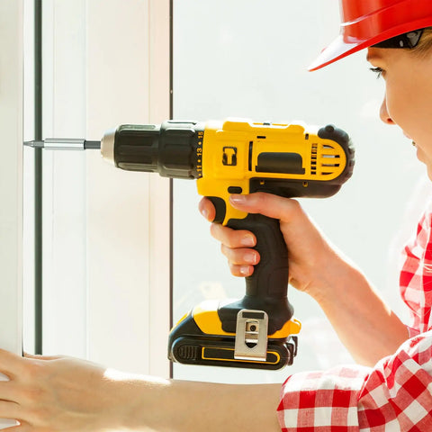Person using a yellow and black power drill on a window frame; focus on the tool's detail and action during repair.