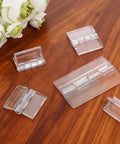 8 Pcs Self Adhesive Clear Plastic Hinges in two sizes on wooden surface, showcasing acrylic transparent design for DIY boxes and aquarium lids.