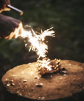 Using Prepper-Ready Large 6 Inch Ferro Rod With Tungsten Carbide Striker And Sharpener to create sparks on wood.