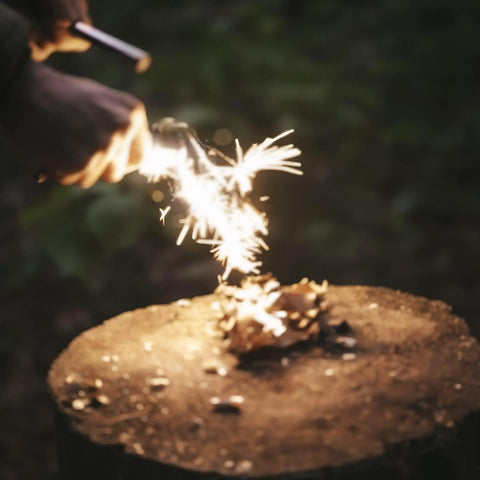 Using Prepper-Ready Large 6 Inch Ferro Rod With Tungsten Carbide Striker And Sharpener to create sparks on wood.