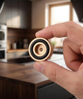 Hand holding golden nonslip rubber pad for cutting boards, aluminum alloy with air circulation gap, kitchen countertop use.