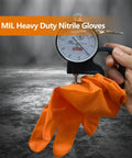 Front view of orange 8-mil nitrile disposable gloves with raised diamond texture, held around a dial gauge.