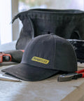 Rainier BCX Bump Cap Made In USA With Low Profile Protection And Ball Cap Style Vibe, Snap Back Closure, Black on workbench.