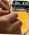 Plug And Play Solderless Breadboard Kit With Six Compact Yellow Protoboard Panels For Rapid Circuit Assembly and Hassle Free Electronics Crafting For Tech Students And Weekend Builders with jumper wires connected.