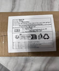 Cardboard package with shipping label placed on a marble surface, showing addresses and recycling symbols.