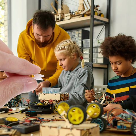 Close-up of Mini Belt Pulley Wheel 0.36 Inch Bore in hand with children assembling RC airplane models in background.