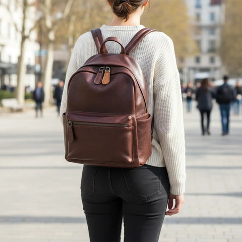 Person wearing a brown leather backpack with decorative zipper tabs visible, standing in an urban setting.