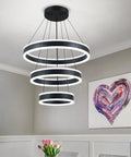 Modern Black LED Ring Chandelier With Three Adjustable Tiered Cylinders hangs flawlessly over dining table with art.