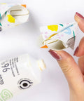 Hand holding a paper craft with floral patterns, using glue from tube labeled 96% natural ingredients.