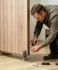 Man installing Heavy Duty Sliding Gate Roller Wheel Sagging Door Support Bearing on wooden sliding door with tools.